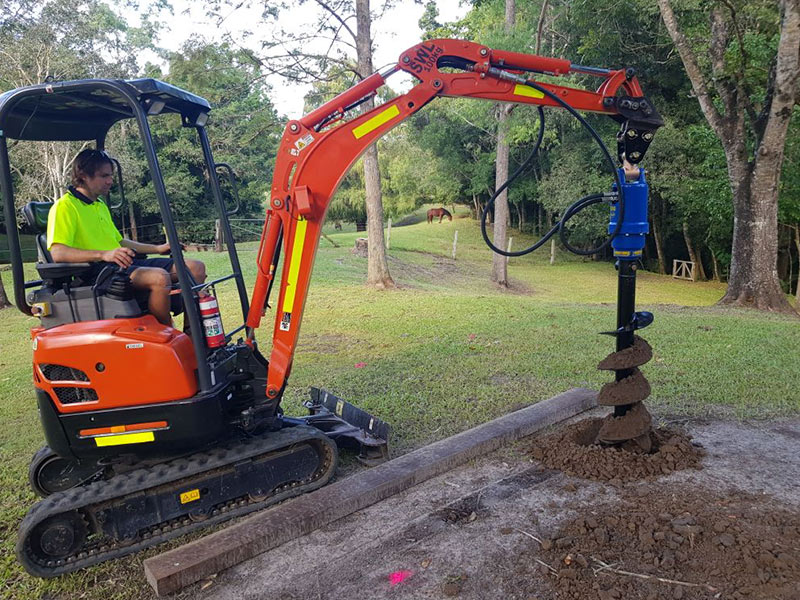 Auger attachment drilling post holes with the mini excavator